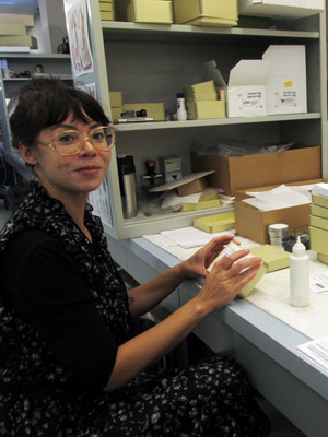 Maria Sheehan Woman gluing label on a box.